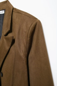 Detail of a brown double-breasted blazer showing collar texture and black buttons