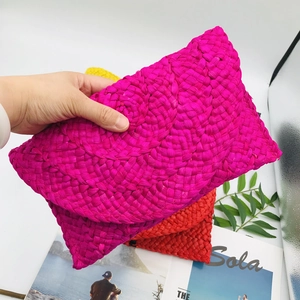 Detail of colorful hand-woven straw clutches in rose red, yellow, and red vibrant tones