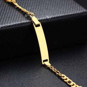 Detailed close-up of a polished gold ID bar bracelet on a textured black jewelry gift box