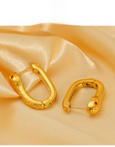 Détails macro des boucles d'oreilles tête de serpent en acier titane doré aux yeux rouges