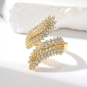 Macro shot of gold olive leaf ring with micro-paved cubic zirconia on stone background