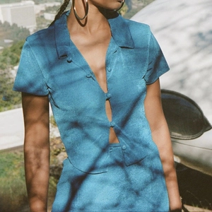Close-up of blue retro cardigan texture and button detail in natural sunlight
