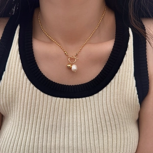 Collier chic à fermoir à bascule doré avec perle et pendentif boule sur un mannequin