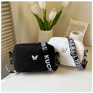 Detail of nylon square bags with butterfly metal buckle and wide lettered shoulder straps