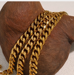 Detailed close-up of chunky gold Cuban chain necklace resting on dark wood display