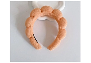 Macro view of orange braided sponge headband with soft plush texture on white display tray