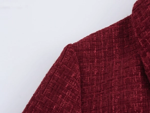 Nahaufnahme des dunkelroten Tweed-Kleides mit Fokus auf die Schultertextur