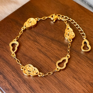 Makroaufnahme der mattgoldenen Hulu-Armkette mit filigranen Blumenanhängern