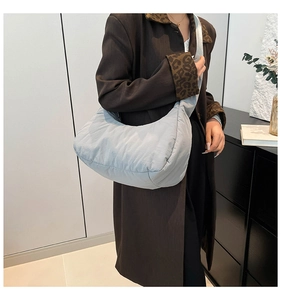 Détail d'un sac demi-lune en nylon matelassé bleu clair avec bandoulière réglable