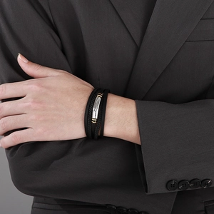 Men's multi-layer leather bracelet with silver metal plate and gold accents on wrist
