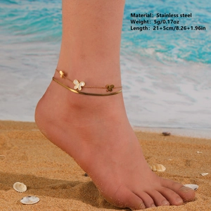 Double-layered golden stainless steel butterfly anklet with white shell on a beach
