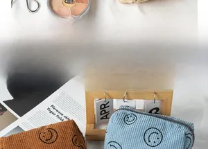 Close-up of corduroy makeup bags in brown and blue with minimalist smile patterns