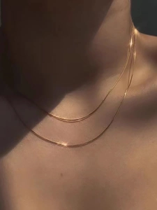 Vista macro de collar de doble capa dorado con cadena de serpiente en el cuello