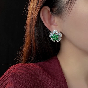 Detailed view of elegant silver flower stud earring with green zircon on a model