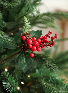 Close-up of artificial Christmas pine branch with red berries and natural pine cones