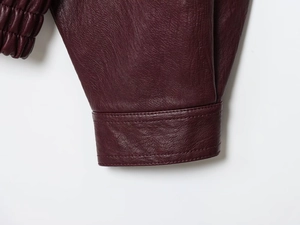Detailed macro view of burgundy PU leather sleeve with elastic cuffs and stitching