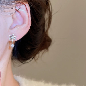 Nahaufnahme des Schneeflocken-Silberohrrings mit Zirkonia-Tropfen am Ohr