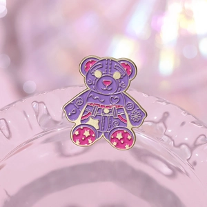 Close-up of a pink bear enamel brooch with gold trim and cute heart star patterns