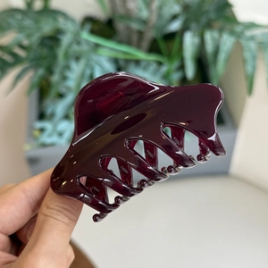 Vue détaillée d'une pince à cheveux en résine rouge vin avec finition brillante