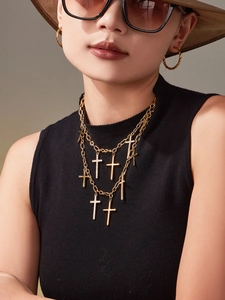 Détail d'un collier croix hip-hop doré multicouche avec pierres sur un mannequin
