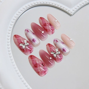 Unghie finte sfumate rosa con fiocco d'argento e perle su vassoio a cuore