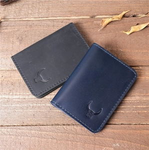 Flat lay of handmade leather card holders in black and blue on a rustic wood surface