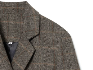 Detail of grey plaid blazer collar and shoulder featuring premium herringbone texture