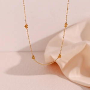 Close-up of gold-plated stainless steel chain with heart pendants and radial texture