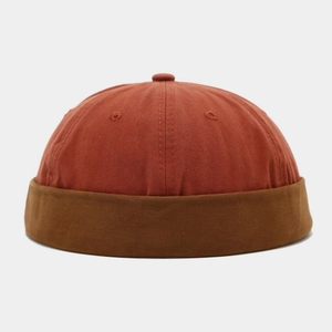 Detail of cotton patchwork brimless docker hat in rust red and dark brown color tones