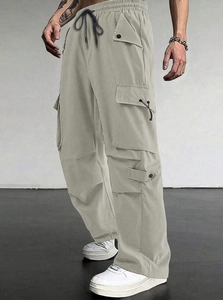 Detail of light gray parachute cargo pants with elastic drawstring waist and side pockets