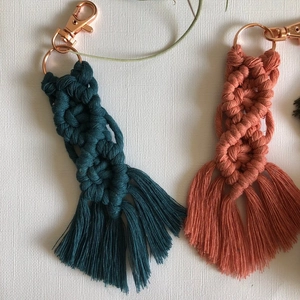 Detail of handmade macrame keychains in teal and coral with elegant fringe and rose gold clasp