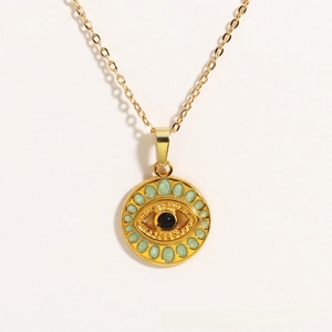 Macro shot of gold-plated evil eye pendant with light green enamel and black center bead