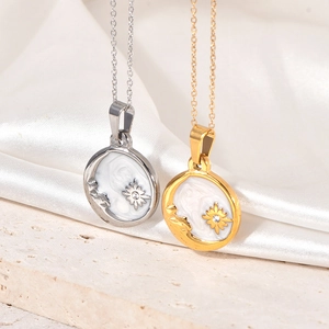 Detail of gold and silver necklaces with moon and star shell pendants on white silk