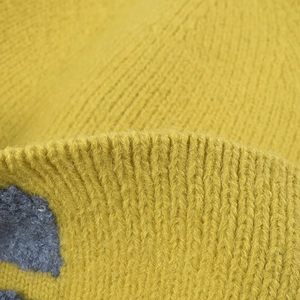 Gros plan d'un bonnet en tricot côtelé jaune moutarde montrant une texture douce et chaude