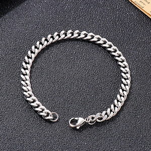 Detail of silver Cuban link chain bracelet with lobster clasp on dark texture background