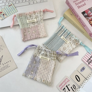 Détail de pochettes à cordon en dentelle avec broderie florale pour bijoux divers