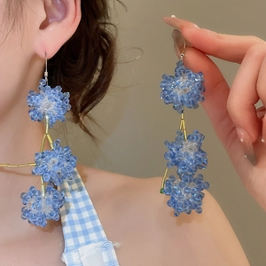 Detail view of long blue crystal beaded tassel earrings worn by a model in casual style