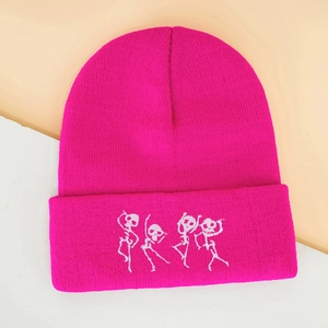Détail du bonnet en tricot magenta avec broderie de quatre squelettes dansants blancs