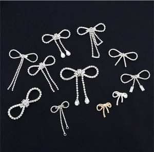 Detailed view of assorted silver bow brooches with sparkling crystals on dark background