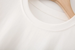 Détail de l'encolure côtelée d'un t-shirt blanc en coton avec des finitions à double surpiqûre
