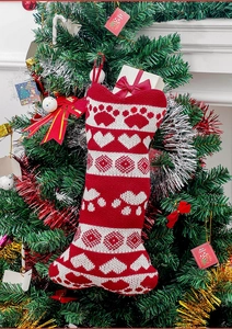 Detailed knit of bone-shaped Christmas stocking with paw prints hanging on a festive tree