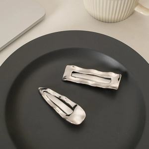 Close-up of two irregular wave silver metal hair clips on a black decorative plate