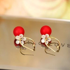 Macro detail of red pearl earrings with zircon plum blossom and golden arc ear hooks