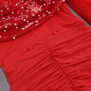 Détail d'une robe de soirée rouge avec paillettes, perles et tissu plissé