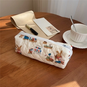 Close-up of quilted floral pencil case with cute rabbit pattern on a wooden desk