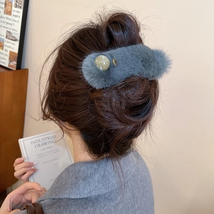 Detail view of blue-grey plush hair clip with pearl embellishment on model hair