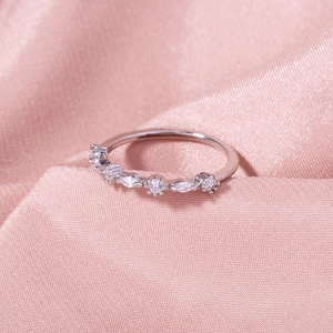 Macro shot of silver ring with marquise and round zircon stones on pink silk