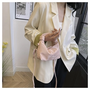Detail of a pink satin crescent bag with decorative knotted handle on a fashion model
