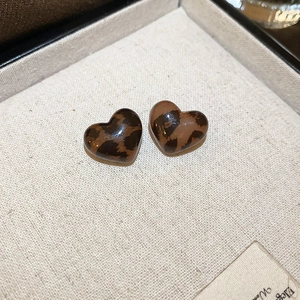 Close-up of heart-shaped earrings with brown leopard tortoiseshell pattern on linen box