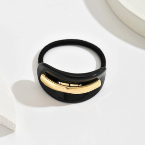 Detail view of black acetate hair tie with elegant gold metal inlay and elastic band